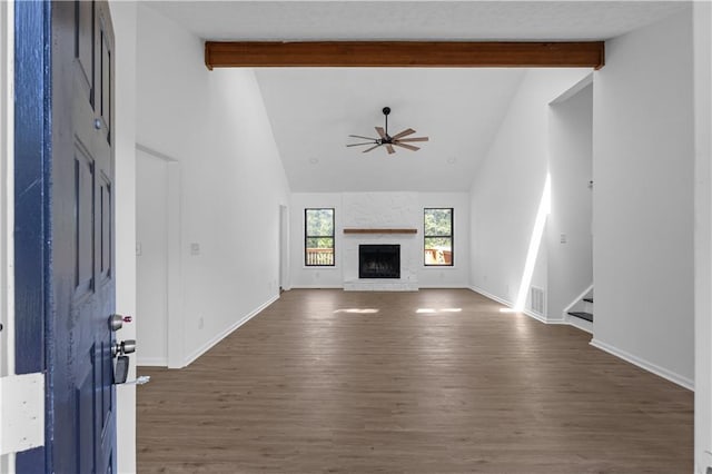 unfurnished living room featuring high vaulted ceiling, ceiling fan, dark wood-type flooring, a fireplace, and beam ceiling