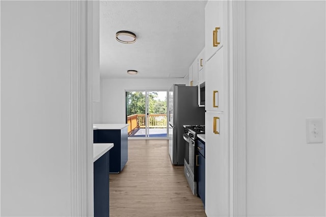 kitchen with blue cabinetry, gas range, light hardwood / wood-style floors, and white cabinetry