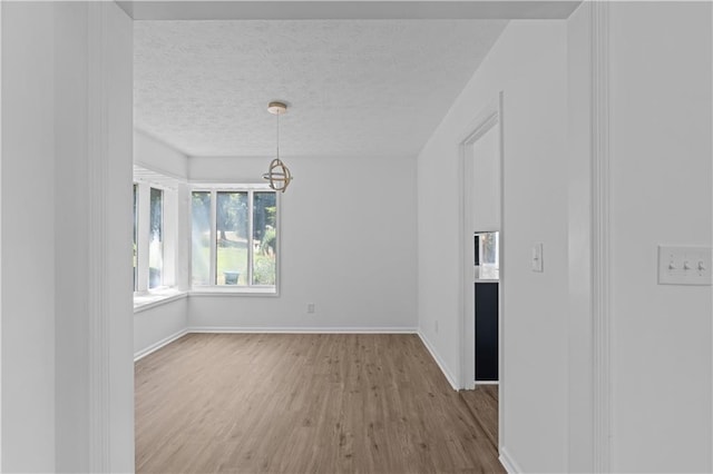 unfurnished room with light hardwood / wood-style floors and a textured ceiling