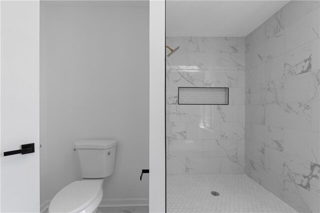 bathroom featuring a tile shower and toilet