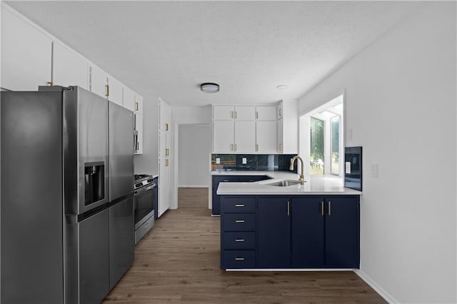 kitchen featuring wood-type flooring, stainless steel appliances, white cabinets, sink, and blue cabinets