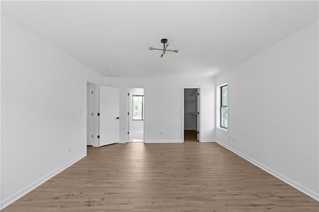 empty room with hardwood / wood-style flooring and a notable chandelier