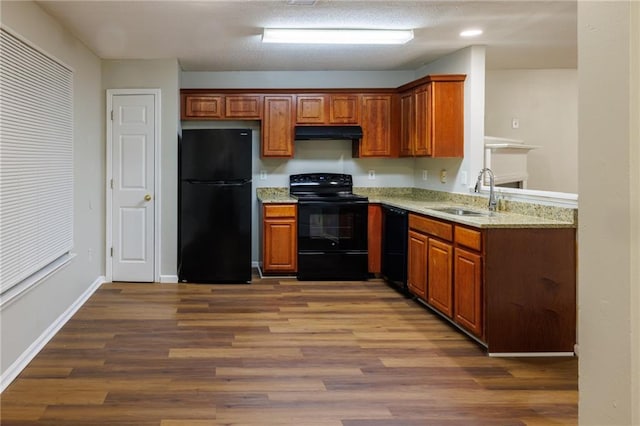 kitchen featuring black appliances, dark wood finished floors, a sink, and exhaust hood