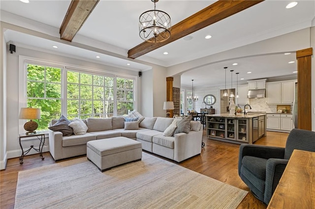 living room featuring beamed ceiling, light wood-style floors, recessed lighting, and an inviting chandelier