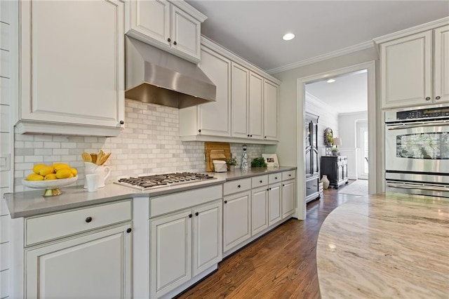 kitchen featuring stainless steel appliances, dark wood-style floors, decorative backsplash, under cabinet range hood, and ornamental molding