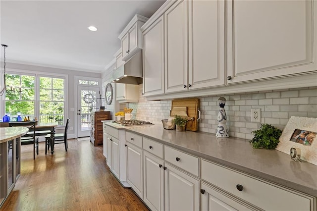 kitchen with white cabinets, decorative backsplash, wood finished floors, and under cabinet range hood