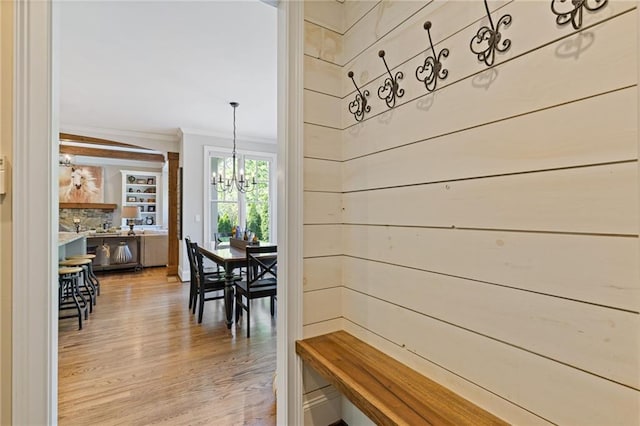 hallway featuring crown molding, a notable chandelier, and light wood-style floors