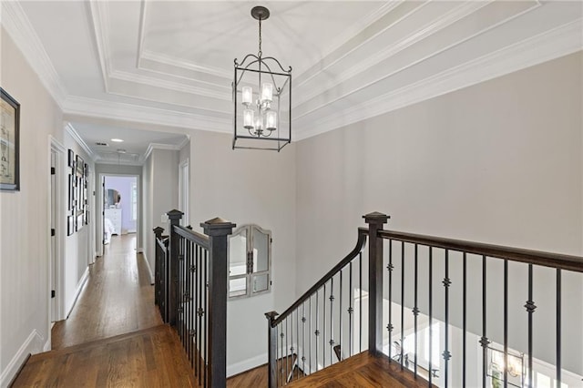 interior space featuring a chandelier, wood finished floors, crown molding, and an upstairs landing