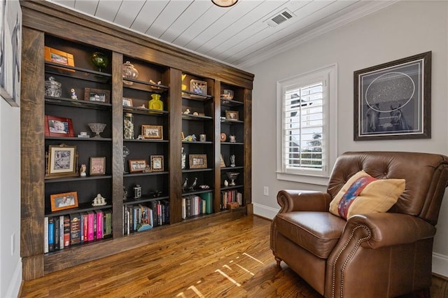 sitting room featuring baseboards, wood finished floors, visible vents, and ornamental molding