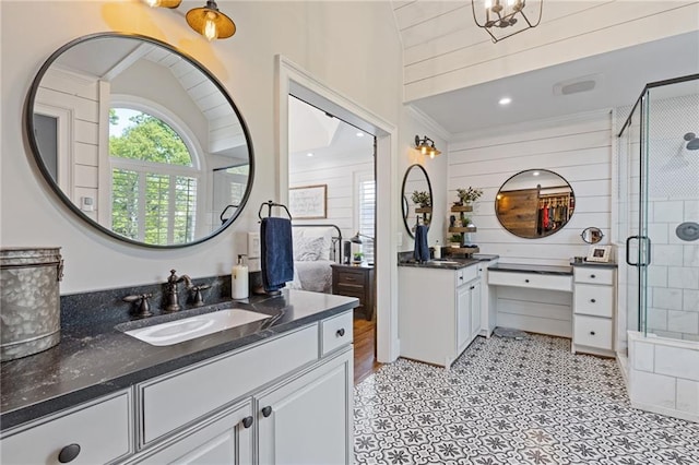 full bath featuring two vanities, a sink, a stall shower, wood walls, and ornamental molding