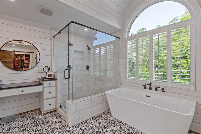 bathroom with wood walls, tile patterned floors, a freestanding bath, tile walls, and a stall shower
