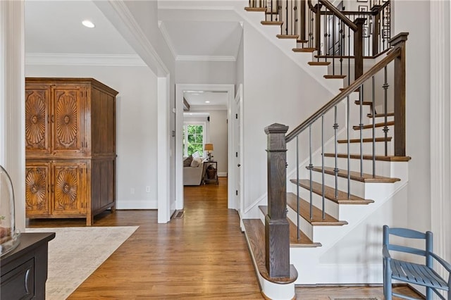 entryway with baseboards, recessed lighting, wood finished floors, stairs, and crown molding