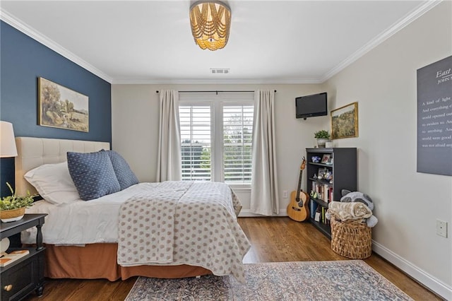 bedroom with wood finished floors, visible vents, and ornamental molding