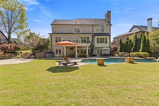 rear view of property with a yard, french doors, a patio area, and an outdoor pool