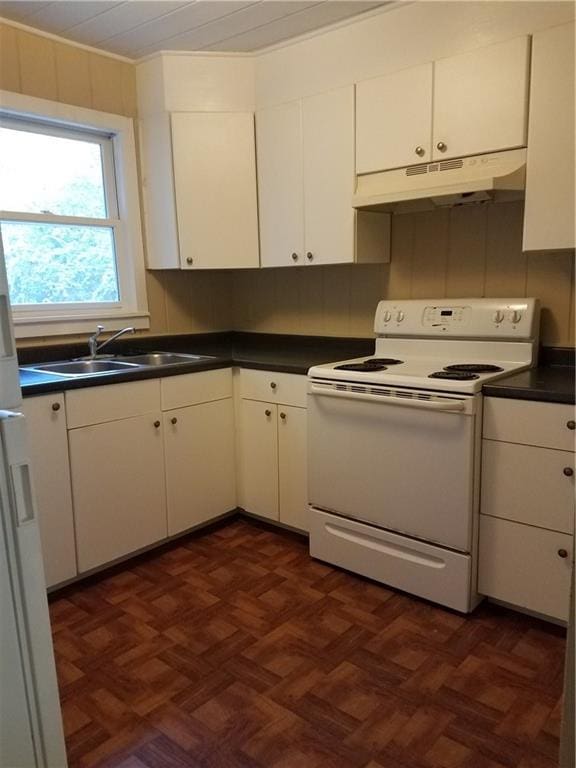 kitchen featuring white range with electric cooktop, dark countertops, white cabinets, a sink, and under cabinet range hood