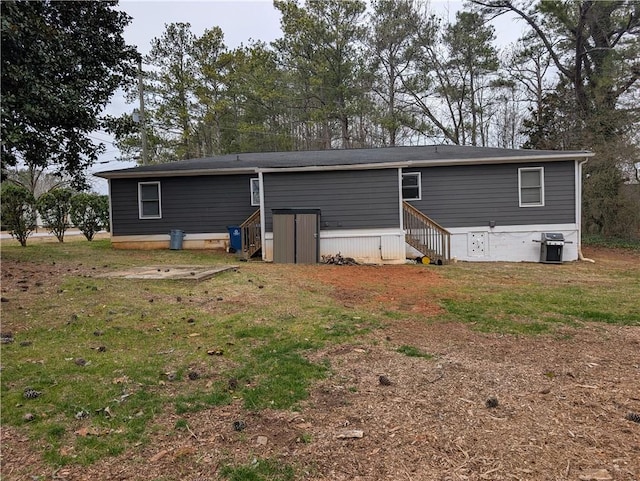 back of property with entry steps and a yard