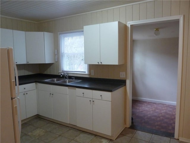 kitchen with freestanding refrigerator, white cabinets, a sink, and dark countertops