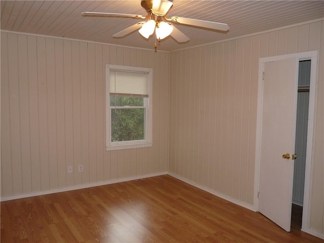 empty room featuring ceiling fan, baseboards, and wood finished floors