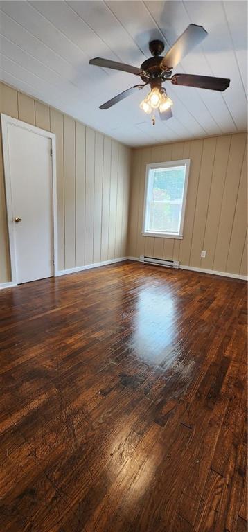 unfurnished room with a baseboard radiator, ceiling fan, baseboards, and hardwood / wood-style flooring