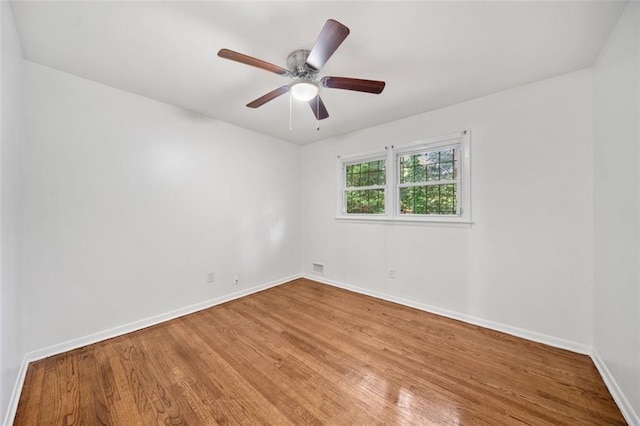 unfurnished room with ceiling fan, baseboards, visible vents, and wood finished floors