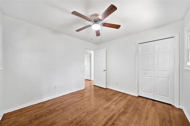 unfurnished bedroom featuring baseboards, a closet, a ceiling fan, and wood finished floors