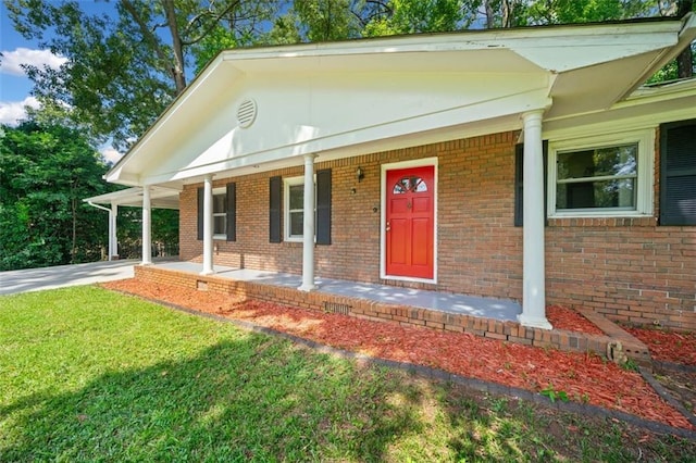 view of front of home with a front lawn, a porch, brick siding, and a carport