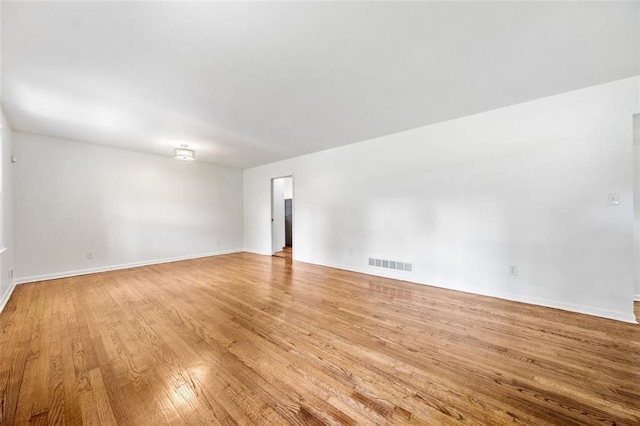 empty room with light wood finished floors, baseboards, and visible vents