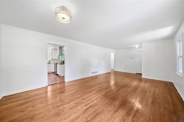 unfurnished living room featuring baseboards, light wood-style floors, and visible vents