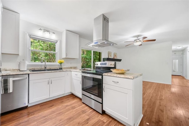 kitchen featuring a sink, a peninsula, stainless steel appliances, island exhaust hood, and plenty of natural light