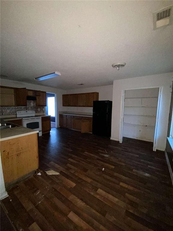 kitchen featuring sink, black fridge, white range with electric stovetop, backsplash, and dark wood-type flooring