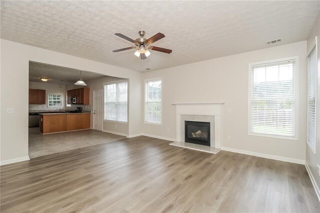 194 Wilhelmina Dr, Austell, GA 30168 - unfurnished living room featuring wood finished floors, ceiling fan, a glass covered fireplace, healthy amount of natural light, and a textured ceiling