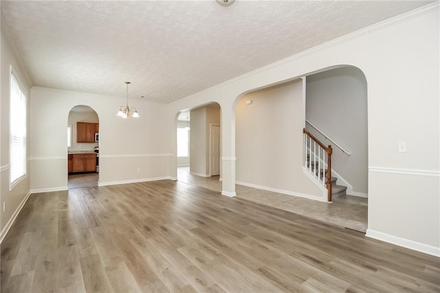 194 Wilhelmina Dr, Austell, GA 30168 - unfurnished living room with arched walkways, a textured ceiling, plenty of natural light, light wood finished floors, and ornamental molding
