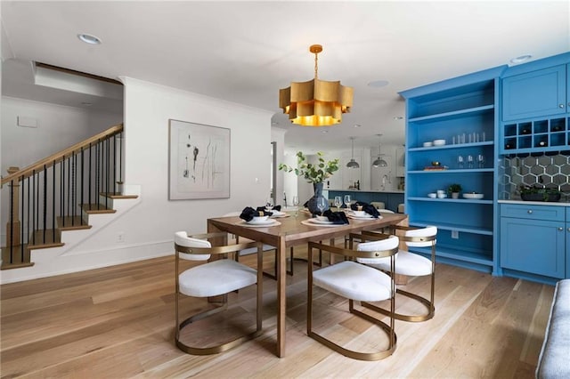 dining room featuring light wood-type flooring, stairway, baseboards, and ornamental molding