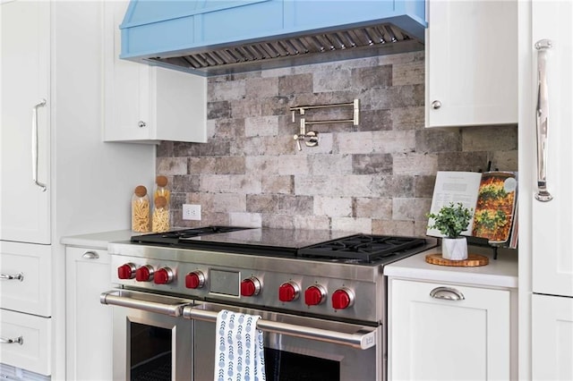 kitchen featuring backsplash, range with two ovens, light countertops, and custom range hood