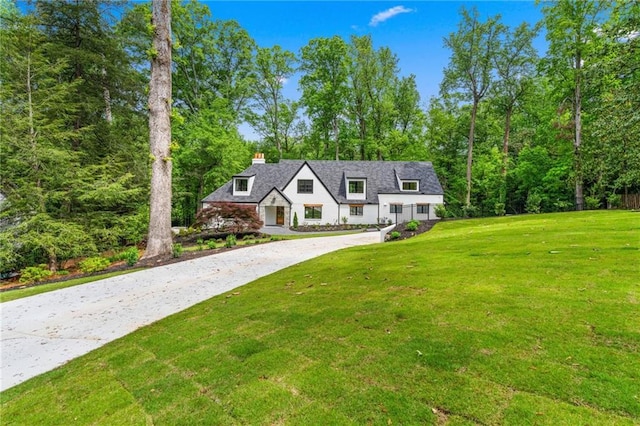 view of front of home with a front lawn, a chimney, and driveway