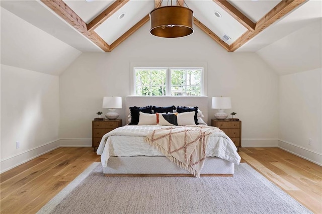 bedroom featuring wood finished floors, baseboards, and vaulted ceiling with beams