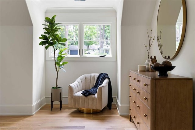living area featuring baseboards, light wood-style floors, and visible vents