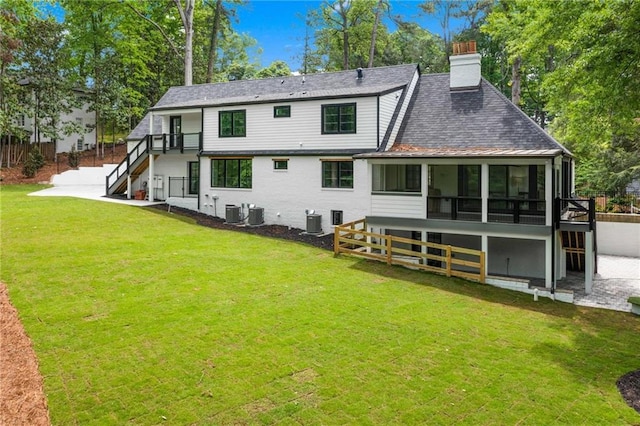 rear view of house featuring a yard, a chimney, central AC, stairs, and a sunroom