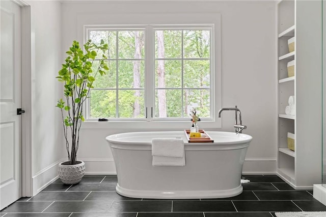 full bathroom with a soaking tub, tile patterned floors, and baseboards