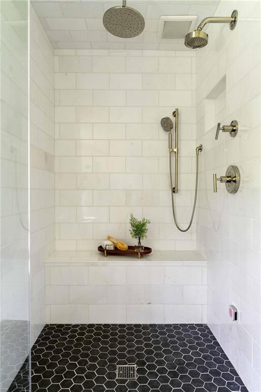 bathroom with visible vents and a tile shower
