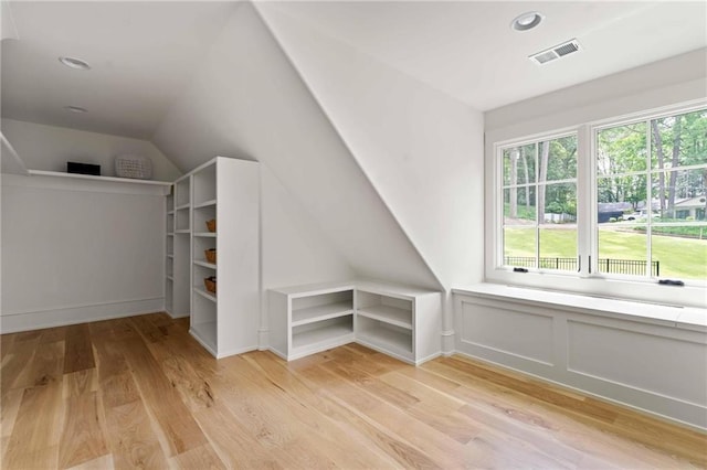 additional living space with light wood-type flooring, visible vents, and vaulted ceiling