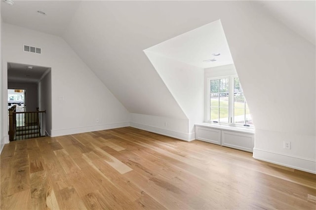 additional living space with lofted ceiling, light wood-style floors, visible vents, and baseboards