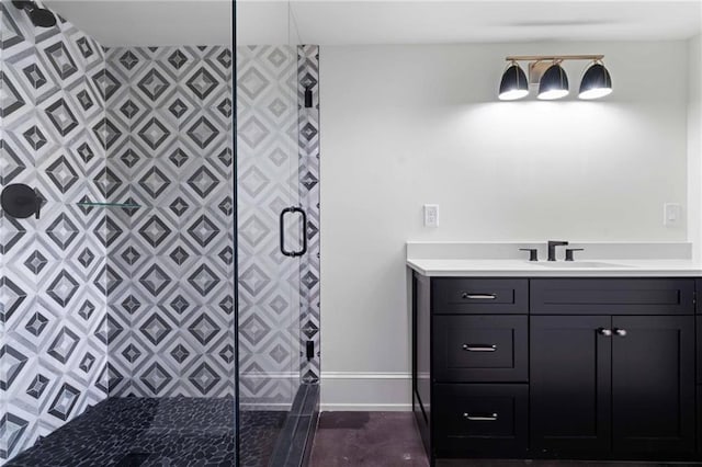 bathroom with a stall shower, vanity, and baseboards