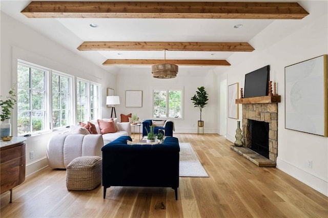 living area with light wood finished floors, beam ceiling, baseboards, and a stone fireplace