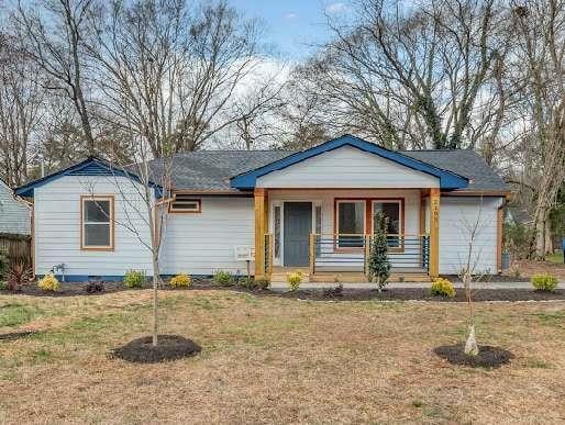 single story home featuring covered porch, a front yard, and an attached garage