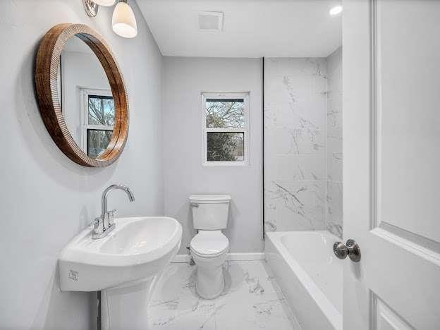 full bathroom featuring toilet, marble finish floor, baseboards, and a sink