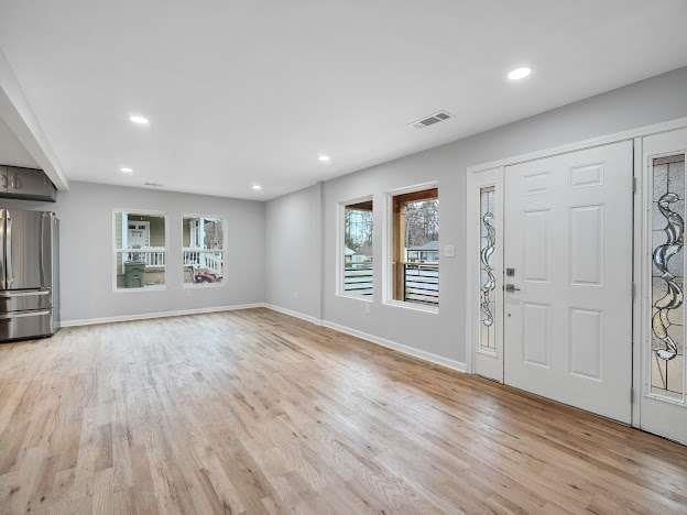 unfurnished living room featuring recessed lighting, wood finished floors, visible vents, and baseboards