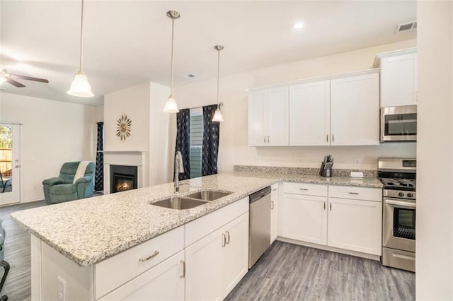 kitchen featuring decorative light fixtures, sink, appliances with stainless steel finishes, and kitchen peninsula