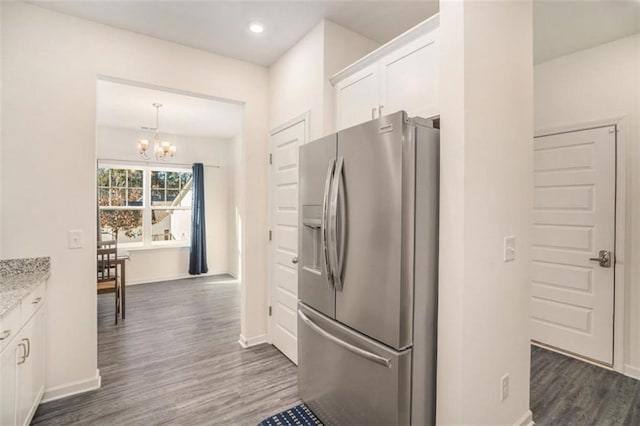 kitchen with stainless steel refrigerator with ice dispenser, white cabinetry, a notable chandelier, and light stone countertops