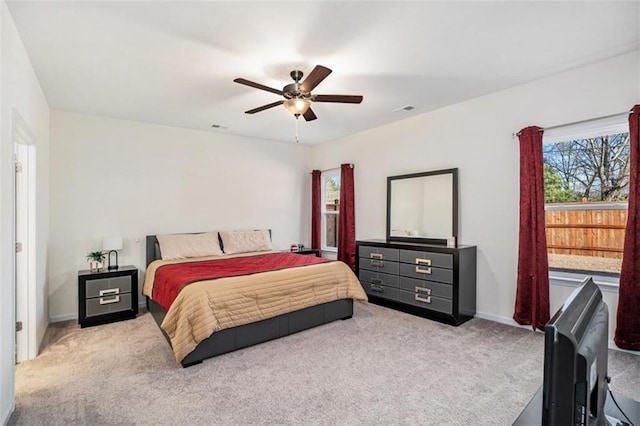 bedroom featuring ceiling fan, light carpet, and multiple windows